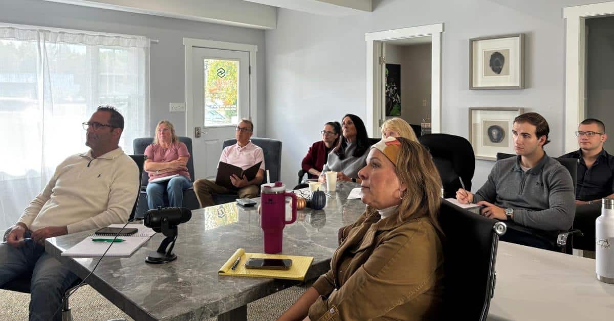 group of real estate agents around a table watching a presentation